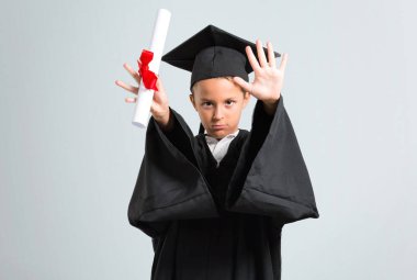 Küçük çocuk gri arka plan üzerinde eliyle stop jest yapma mezun