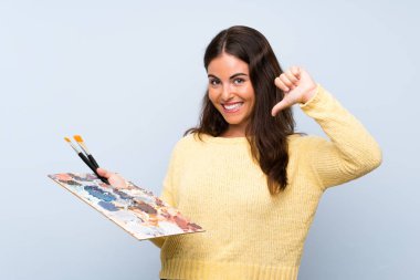 Izole mavi arka plan üzerinde genç sanatçı kadın gururlu ve kendini tatmin