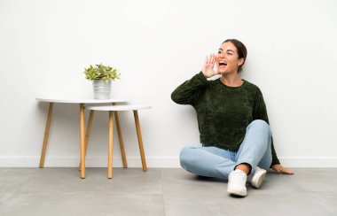 Genç bir kadın yerde oturuyor ve ağzı açık bağırıyor.