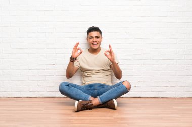 Genç adam parmakları ile ok işareti gösteren katta oturan