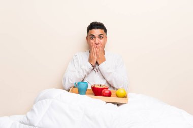 Sürpriz yüz ifadesi ile yatakta kahvaltı genç adam