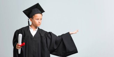 Küçük çocuk gri arka planda avuç üzerinde copyspace hayali tutarak mezun