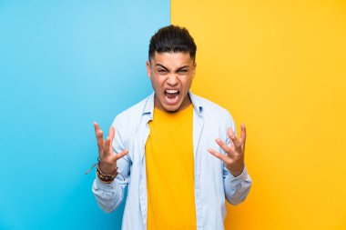 Izole renkli arka plan üzerinde Genç adam mutsuz ve bir şey ile sinirli