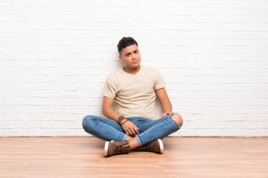 Genç adam yerde oturmuş bir fikir düşünüyor.