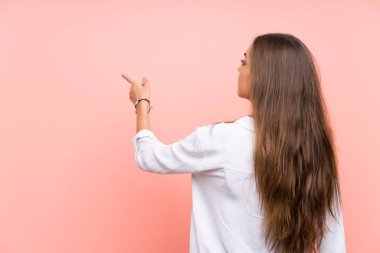 İzole pembe arka plan üzerinde genç kadın işaret parmağı ile geri işaret