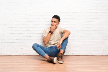 Genç adam yerde oturmuş bir fikir düşünüyor.