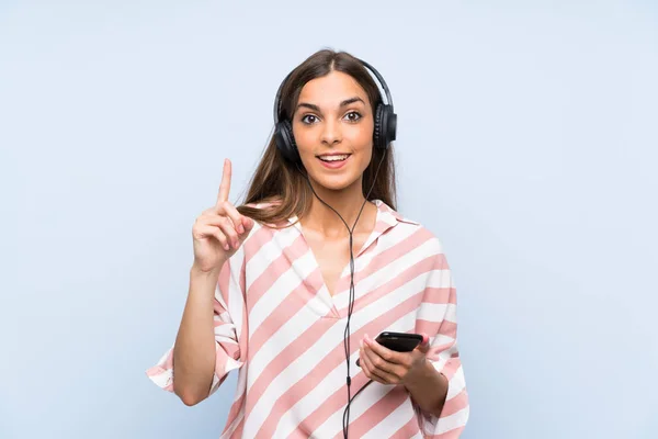 Jeune Femme Écoutant Musique Avec Mobile Sur Mur Bleu Isolé — Photo