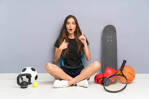 驚きの表情で床に座る若いスポーツ女性 — ストック写真