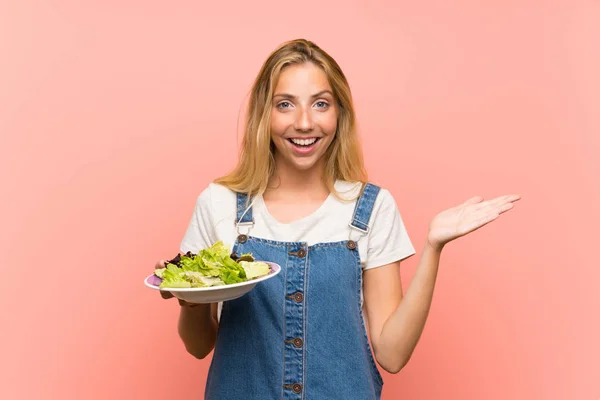 Blonde Junge Frau Mit Salat Über Isolierter Rosa Wand Mit — Stockfoto