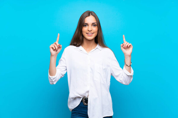 Молодая женщина на изолированном синем фоне указывает на отличную идею