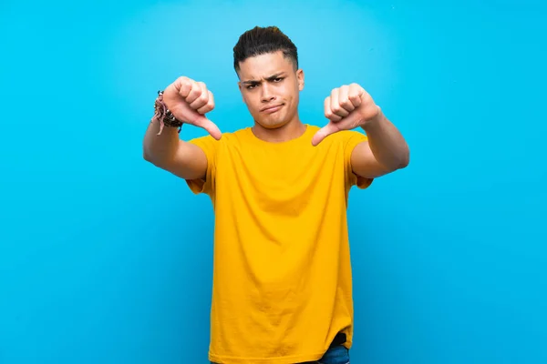 Young Man Yellow Shirt Isolated Blue Background Showing Thumb — Stock Photo, Image