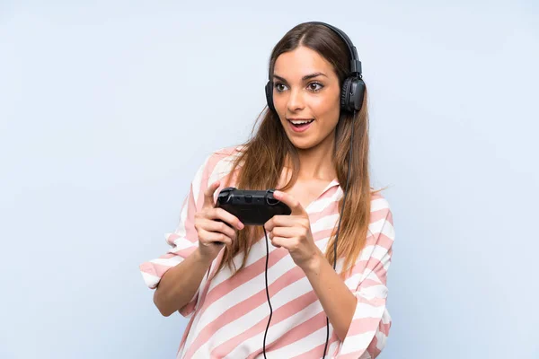 Junge Frau spielt mit Videospiel-Controller über isolierte blaue Wand — Stockfoto