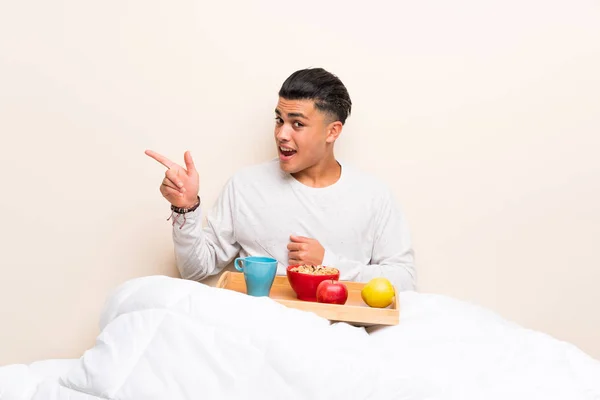 Joven Desayunando Cama Apuntando Con Dedo Hacia Lado —  Fotos de Stock