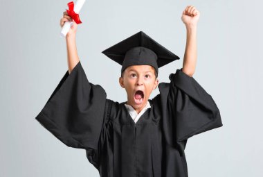 Küçük çocuk gri arka plan üzerinde bir zafer kutluyor mezun