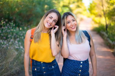 Bir parkta müzik dinleyen sırt çantası ile genç öğrenci kızlar