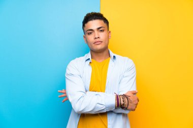 Izole renkli arka plan üzerinde genç adam kollarını çapraz tutmak