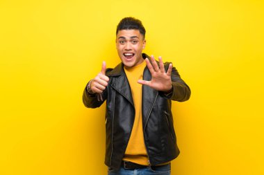 Izole sarı arka plan üzerinde genç adam parmakları ile altı sayma