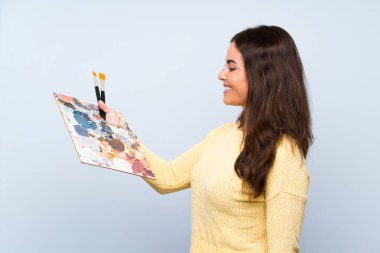 Mutlu ifade ile izole mavi arka plan üzerinde genç sanatçı kadın