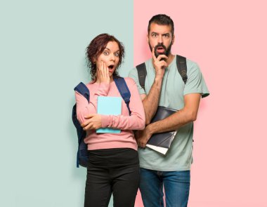 Sırt çantaları ve kitapları olan iki öğrenci, renkli duvara bakarken şaşırıp şok edebildiler.