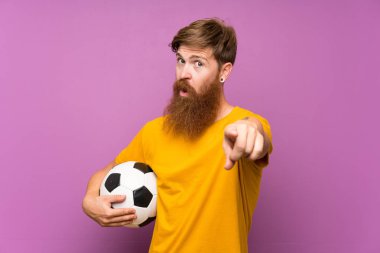 Uzun sakallı kızıl saçlı adam kendinden emin bir ifade ile size izole mor duvar noktaları parmak üzerinde bir futbol topu tutan