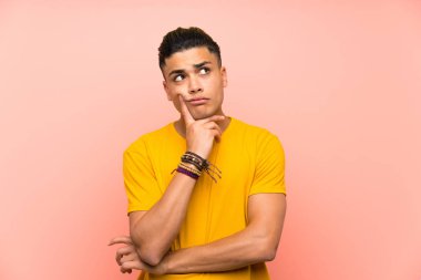 Izole pembe duvar üzerinde sarı gömlekli genç adam bir fikir düşünme