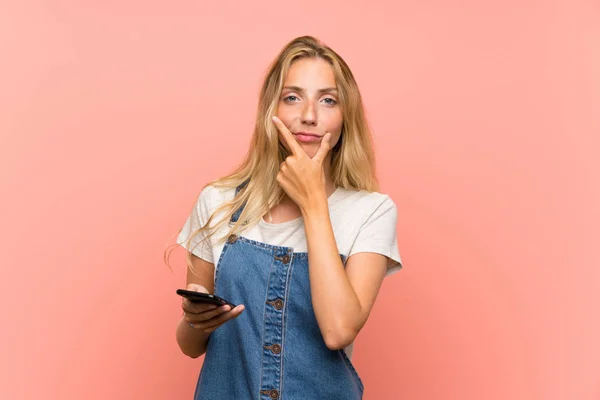 Blonde Jonge Vrouw Met Een Mobiele Telefoon Geïsoleerde Roze Muur — Stockfoto