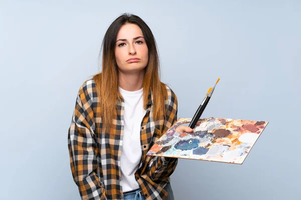 Jovem Pintor Mulher Sobre Fundo Azul Isolado Com Expressão Triste — Fotografia de Stock