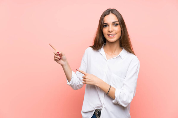 Молодая женщина на изолированном розовом фоне указывая пальцем в сторону