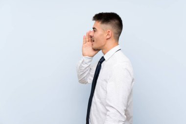 Izole mavi arka plan üzerinde Yakışıklı işadamı ağzı tamamen açık bağırıyor