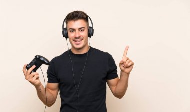 Genç yakışıklı adam izole arka plan üzerinde bir video oyunu denetleyicisi ile oynayan harika bir fikir işaret