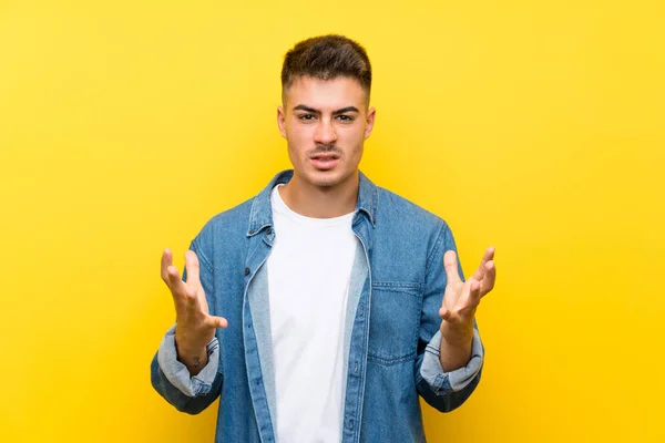 Young handsome man over isolated yellow background unhappy and frustrated with something
