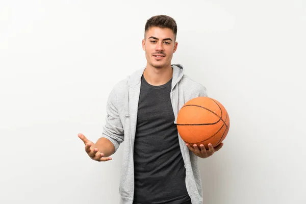 Спортсмен над ізольованою білою стіною з м'ячем баскетболу — стокове фото