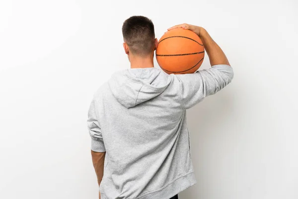 Hombre deportivo sobre pared blanca aislada con pelota de baloncesto — Foto de Stock