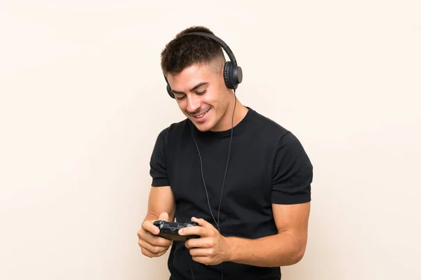 Jovem homem bonito jogando com um controlador de videogame sobre fundo isolado — Fotografia de Stock