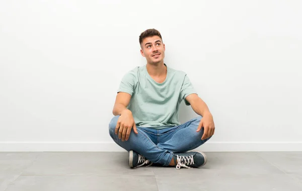 Mladý Pohledný Muž Sedící Podlaze Smějící Vzhlížející — Stock fotografie