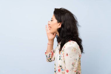 Soyutlanmış mavi arka planda genç bir kadın ağzı açık bağırıyor.