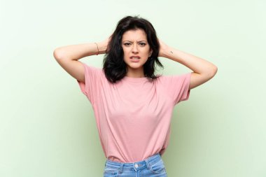Izole yeşil arka plan üzerinde genç kadın sinirli ve baş elleri alır