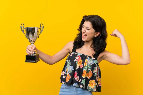 Jovem Mulher Sobre Fundo Amarelo Isolado Segurando Troféu — Fotografia de Stock