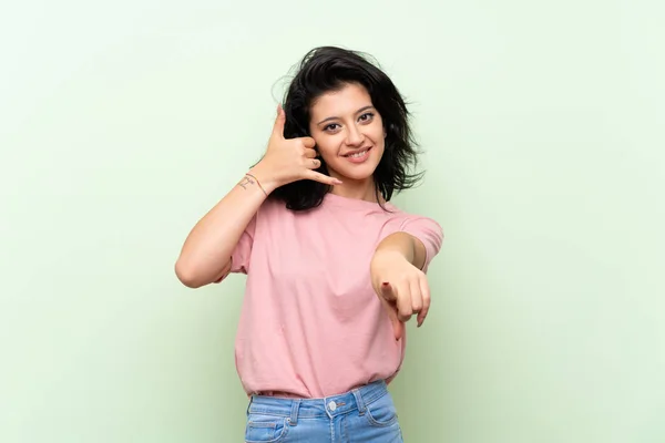 Mujer Joven Sobre Fondo Verde Aislado Haciendo Gesto Teléfono Apuntando —  Fotos de Stock