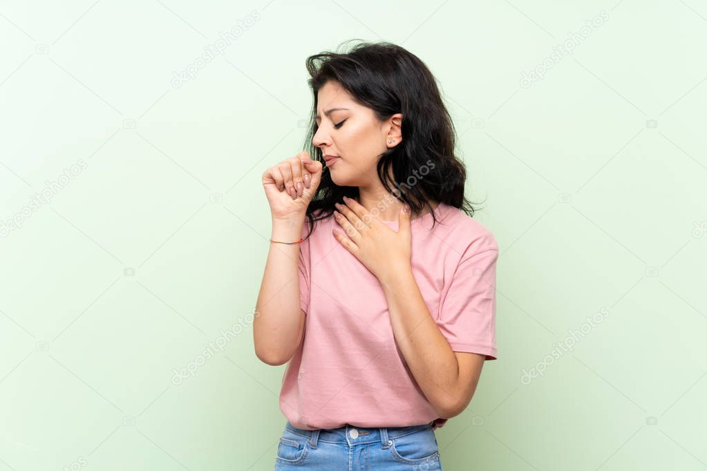 Young woman over isolated green background is suffering with cough and feeling bad