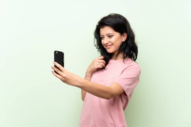 İzole yeşil arka plan üzerinde genç kadın selfie yapma