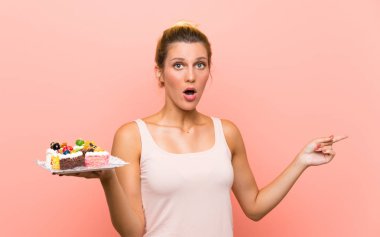 Genç sarışın kadın farklı mini kek çok tutan şaşırttı ve yan işaret