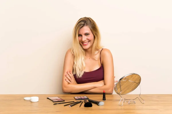 Junge Blonde Frau Mit Kosmetik Auf Einem Tisch Lacht — Stockfoto