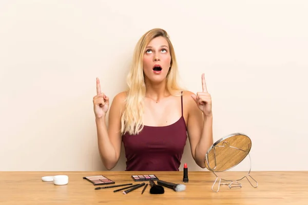 Jeune Femme Blonde Avec Cosmétique Dans Une Table Pointant Avec — Photo