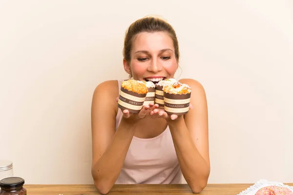 Young woman with lots of different mini cakes in a table — Stock Photo, Image