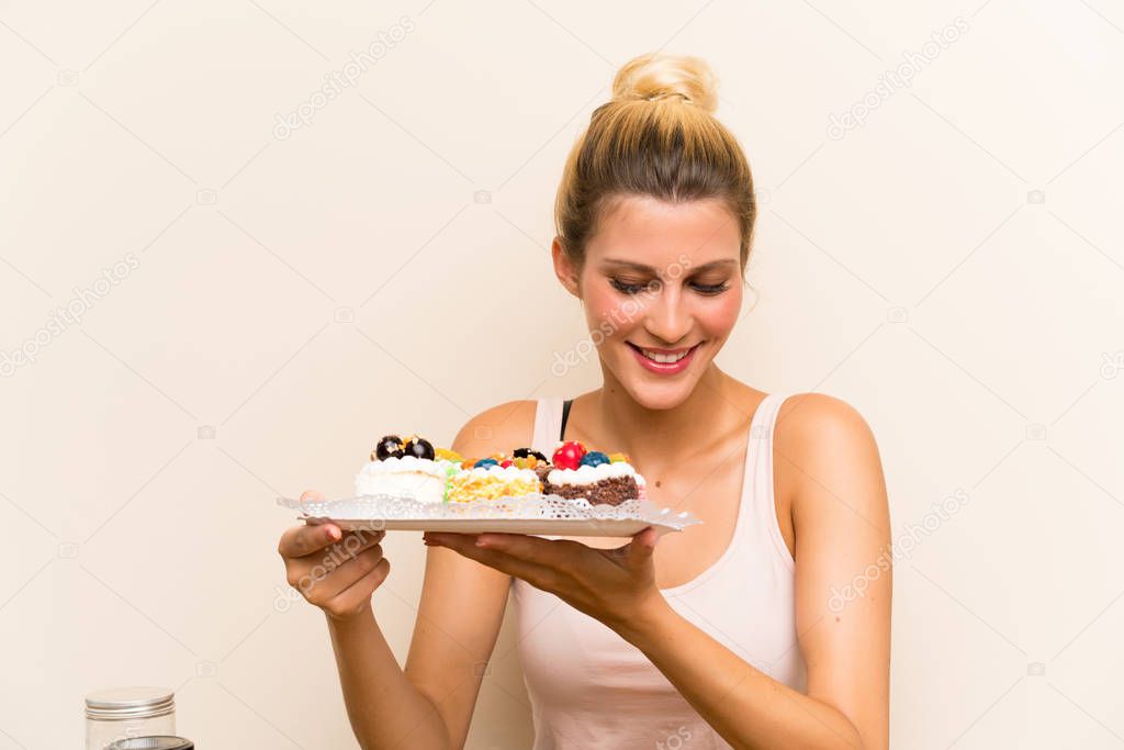 Young woman with lots of different mini cakes in a table