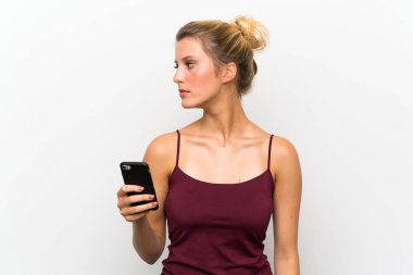 Genç sarışın kadın cep telefonu kullanarak yan görünümlü