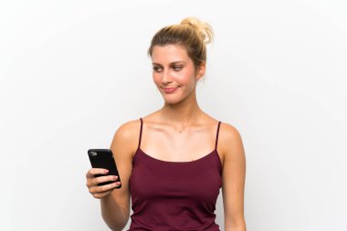 Genç sarışın kadın ayakta cep telefonu kullanarak ve yan bakıyor