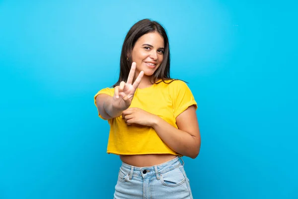 Chica Joven Sobre Fondo Azul Aislado Sonriendo Mostrando Signo Victoria — Foto de Stock