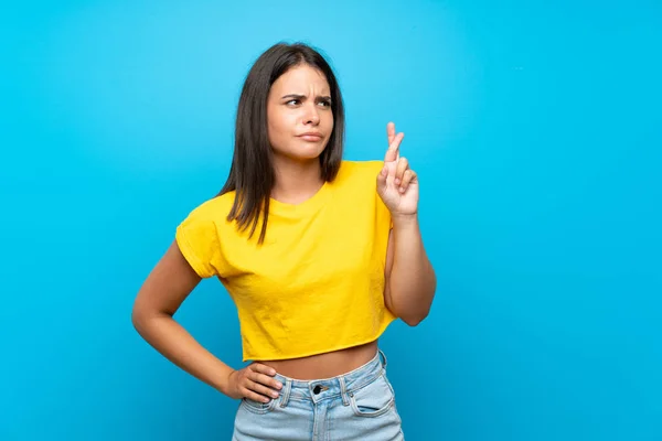 Menina Sobre Fundo Azul Isolado Com Dedos Cruzando Desejando Melhor — Fotografia de Stock